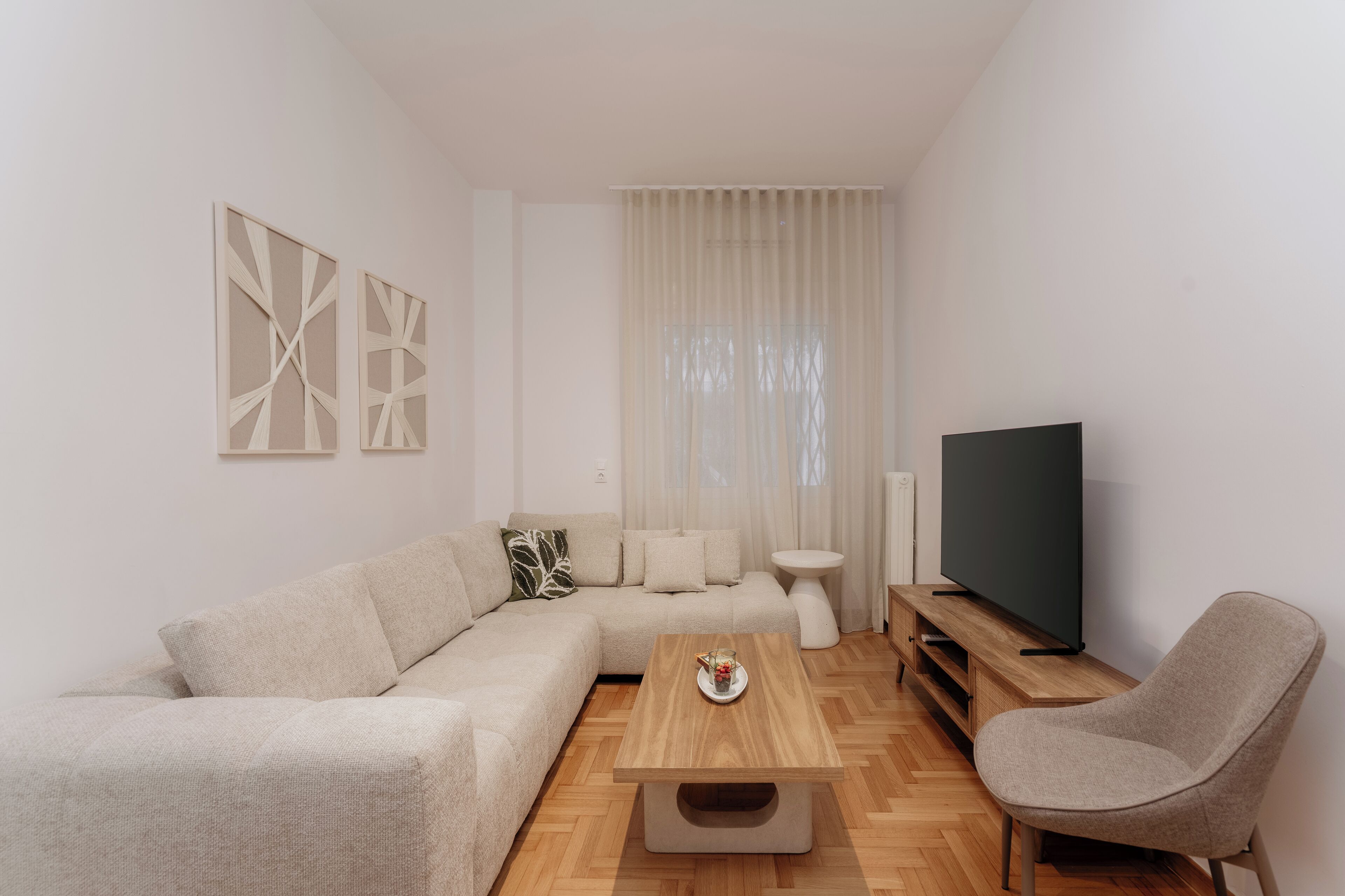 A modern living room with a sectional sofa, a coffee table, a TV, and a side table.