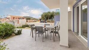 Une terrasse avec une table et des chaises, un scooter et un bâtiment en arrière-plan.