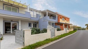 Un immeuble résidentiel moderne doté d’une entrée sécurisée, d’un espace extérieur couvert et d’un escalier menant au deuxième étage.