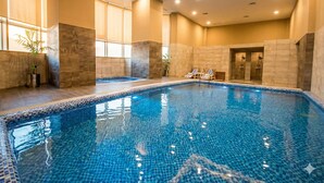 Una piscina interna con pareti e pavimento piastrellati, e un soffitto con illuminazione a incasso.