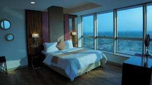 Una moderna camera d'albergo con un ampio letto, vista sulla città e una grande finestra.