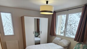 Une chambre avec deux lits, une armoire et une fenêtre.