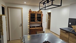 Un espace repas comprenant une table, des chaises, un meuble avec des portes en verre et un luminaire suspendu.