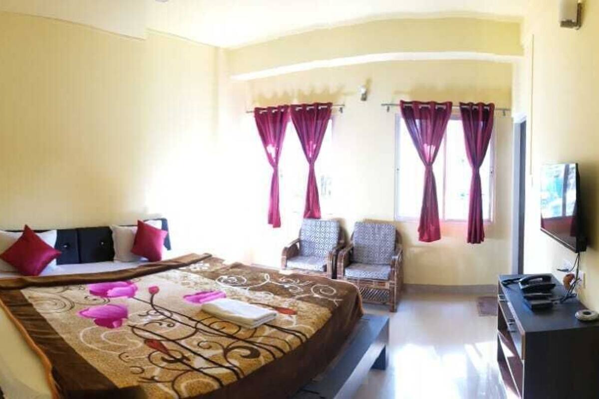 A bedroom with a bed, a chair, a desk, and a TV.