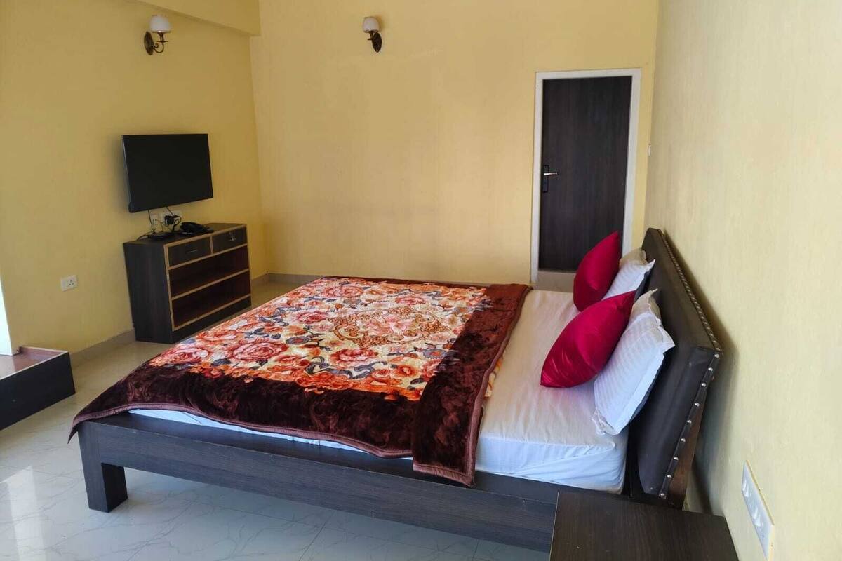 A bedroom with a bed, a TV, a wardrobe, and a door.