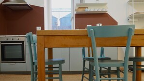 Une cuisine avec une table et des chaises en bois, un four encastré et une fenêtre donnant sur des silos.