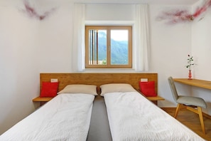 A room with a bed, a desk, a chair, a window with a view of mountains, and a decorative wall piece. - Apartment Maruna with Mountain View, Private Terrace and Wi-Fi (Magrè allʼ Adige)