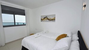 A hotel room with a large bed, a window with a view, and a painting on the wall. - Ariston  First Line Lake View (Tiberias)