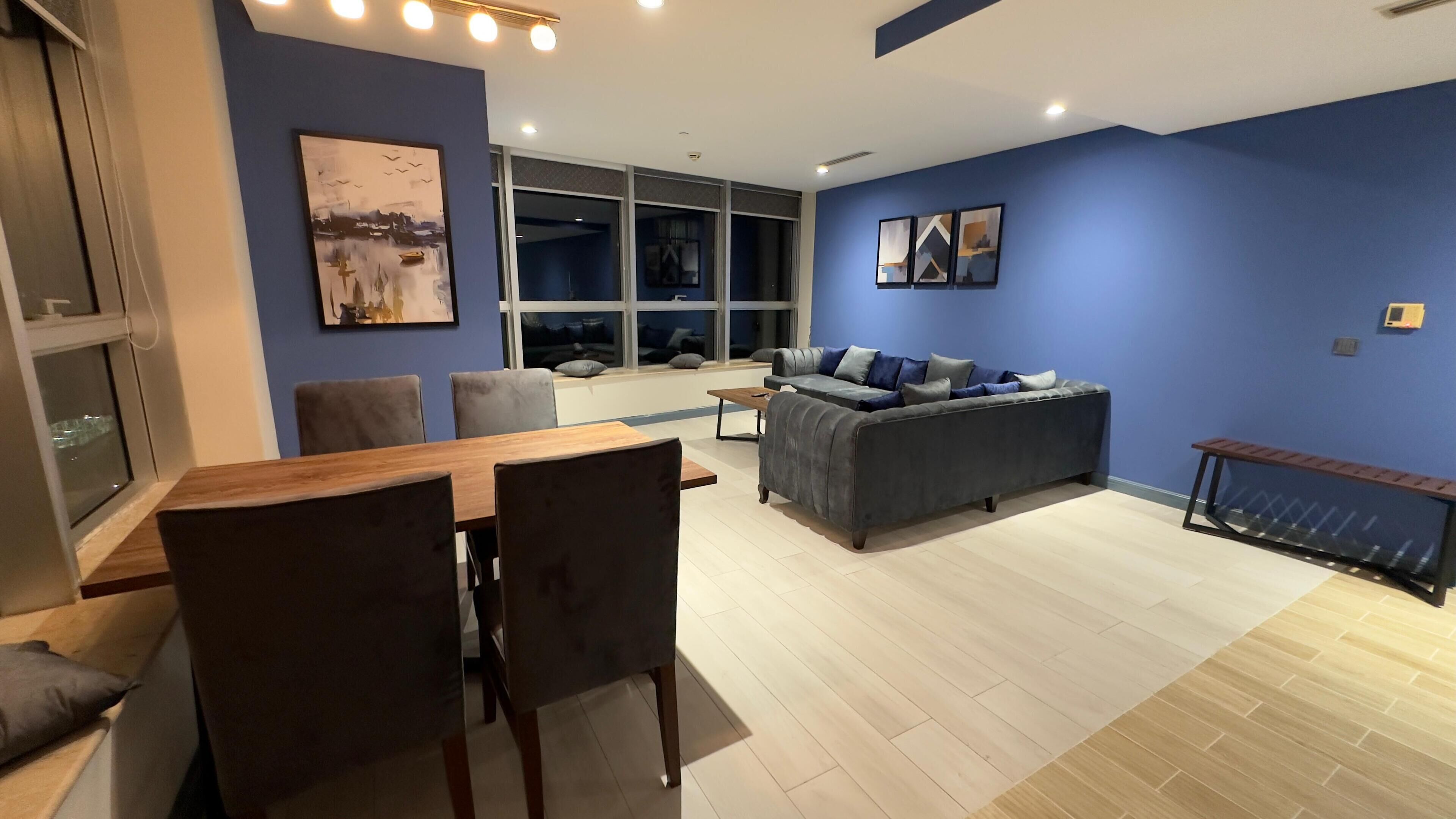 Una sala de estar moderna con comedor, que incluye un sofá, una mesa de centro y una mesa de comedor de madera con sillas.