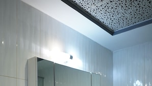 A bathroom with a white sink, a mirror, a hairdryer, and a towel rack. - The Grand Skyline Corner Suite (Islamabad)