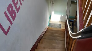 Una escalera con barandilla, una pared con la palabra 'LIBERTY' pintada y una puerta al final.