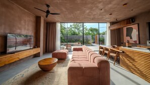 A modern living room with a large TV, a sofa, a dining area, and a kitchen counter. - Keluoli villas Bingin (Pecatu)