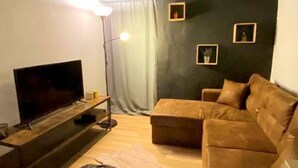 Un salon moderne avec un téléviseur à écran plat, un canapé, une table basse et un lampadaire.