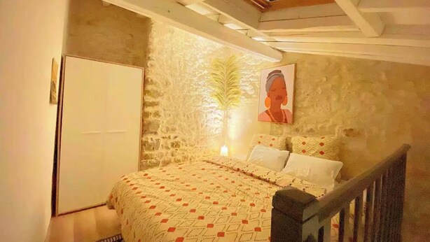 Une chambre à coucher avec un lit, une porte en bois, un mur en pierre et un tableau.