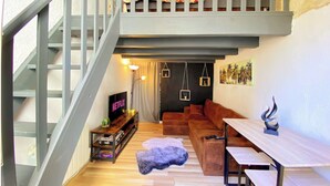 Un espace de vie de style loft comprenant un escalier, un canapé, une table basse et un téléviseur.