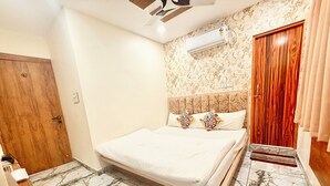 A bedroom with a bed, a wooden door, an air conditioning unit, and a patterned wall. - Near Mahakal Temple Hotel M L Y  Ujjain (Ujjain)