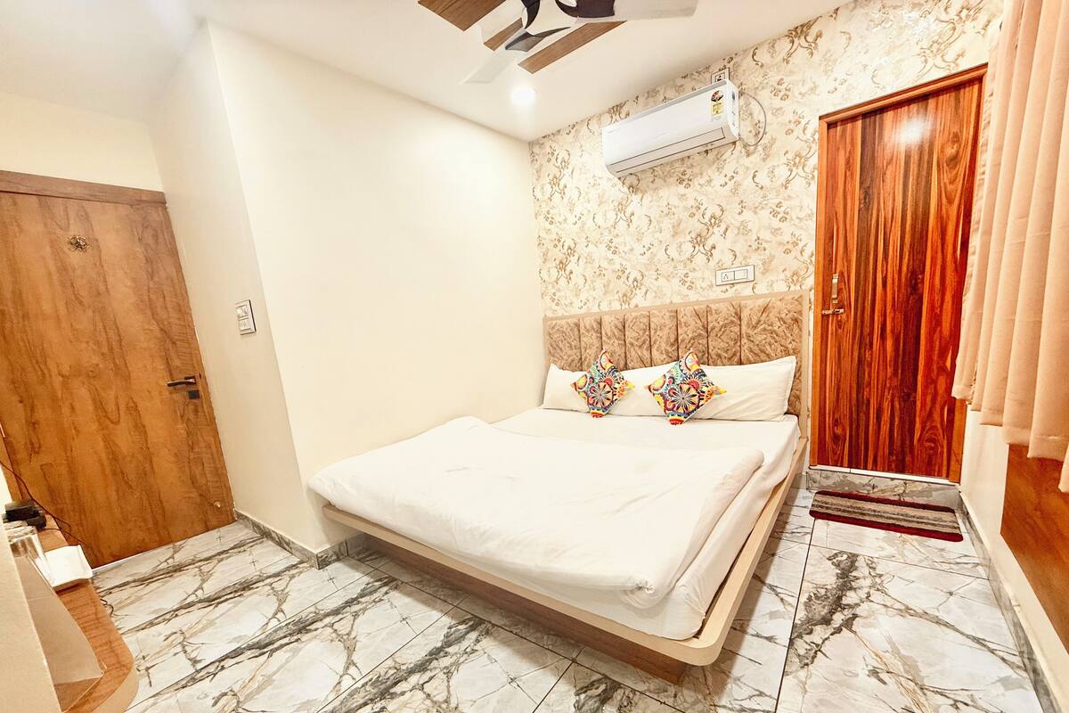 Ein Schlafzimmer mit einem Bett, einer Holztür, einer Klimaanlage und einer Wand mit Muster.