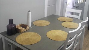 Een eettafel met geweven placematen, een keukenrol en een decoratieve fles.