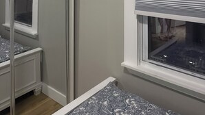 Een slaapkamer met een raam, een radiator en een spiegel.