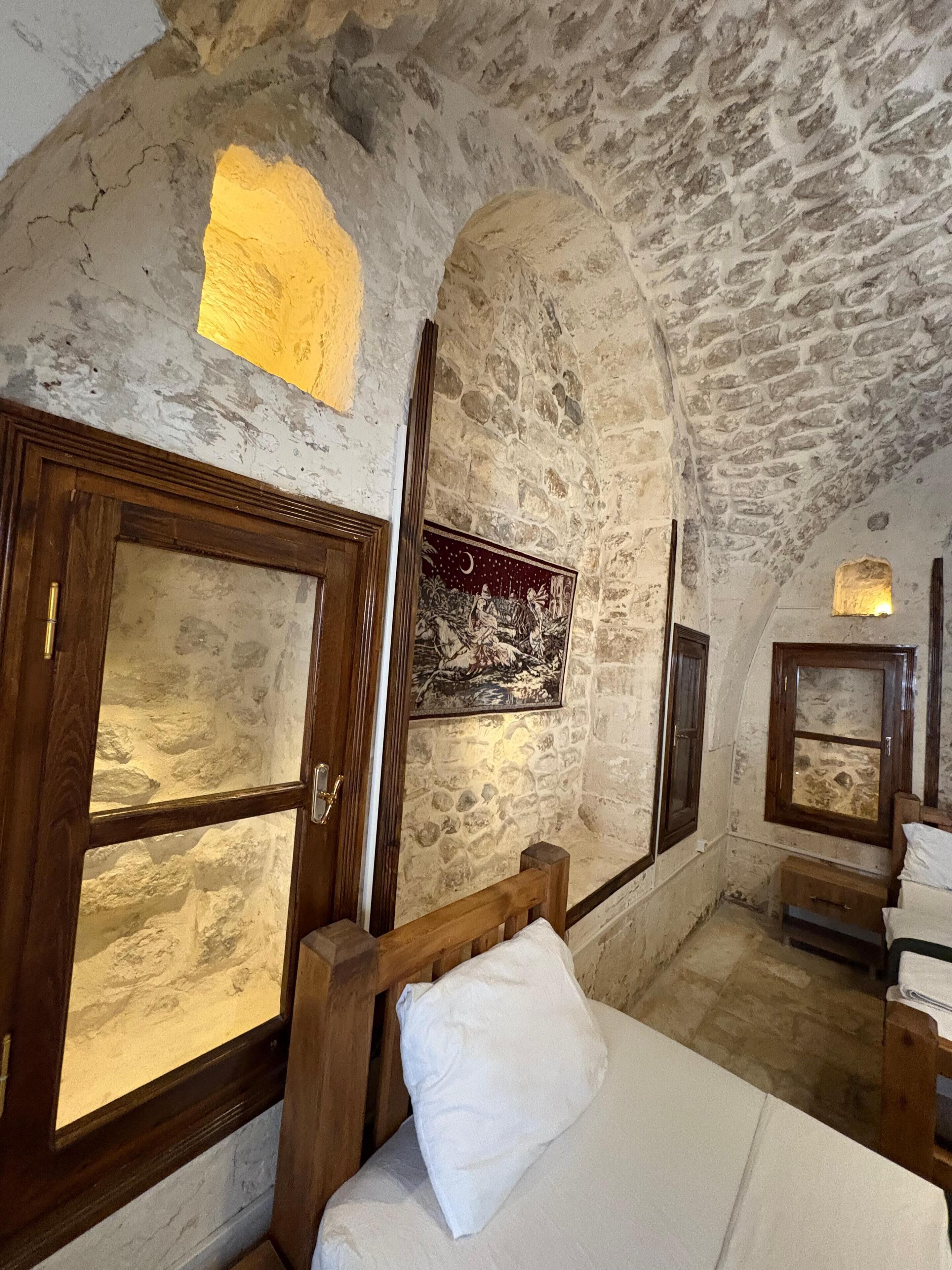 Una habitación rústica con paredes de piedra, una cama, muebles de madera y un cuadro en la pared.