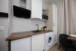 Una cocina funcional con lavadora, microondas y lavamanos.