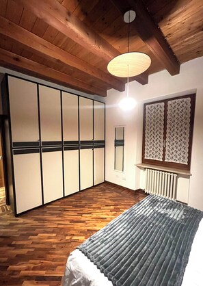 A room with wooden flooring, a bed with a grey blanket, a wooden ceiling, and a large wardrobe with sliding doors. - In the heart of the historic center a few steps from the Arena and Juliet's Balcony (Verona)