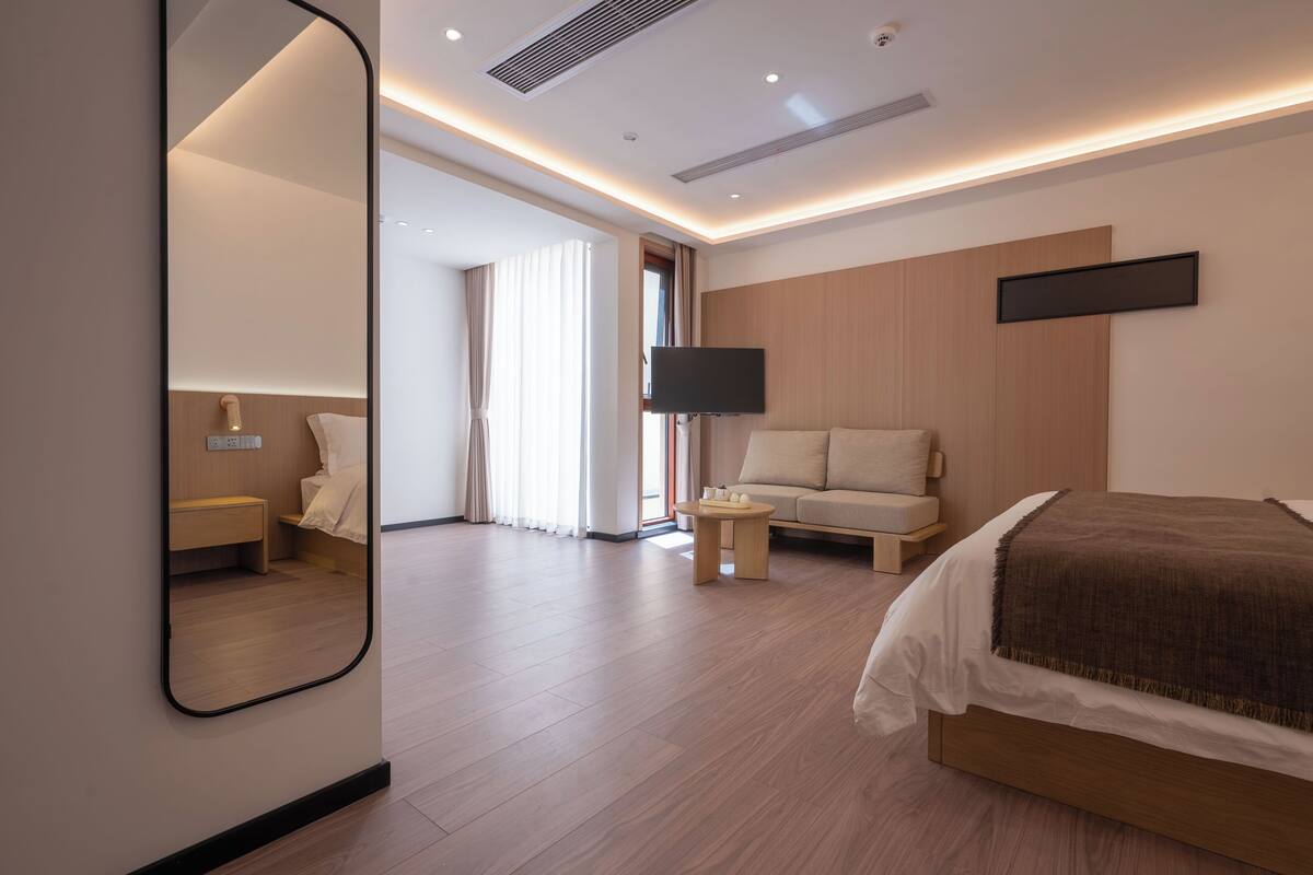 Ein modernes Hotelzimmer mit einem großen Bett, einer Couch, einem an der Wand befestigten Fernseher und einem kleinen Tisch.