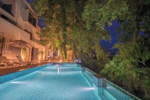 A swimming pool with a view of a building and trees at night. - Mengxi Bieyuan Forest Resort Hotel (Huangshan)