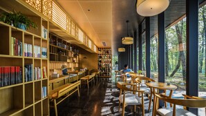 A library with bookshelves, wooden tables, and chairs. - Mengxi Bieyuan Forest Resort Hotel (Huangshan)