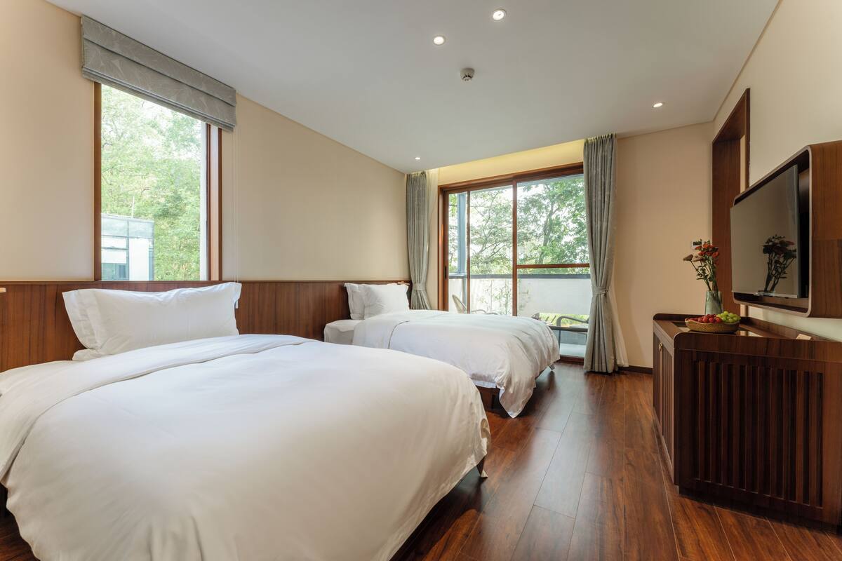 Ein Hotelzimmer mit zwei Betten, einem Fernseher und einem Fenster mit Vorhängen.