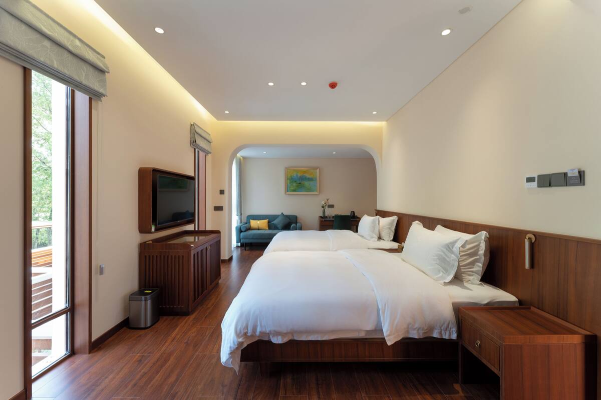 Ein modernes Hotelzimmer mit einem großen Bett, einem Fernseher, einer kleinen Sitzecke und Blick ins Freie.