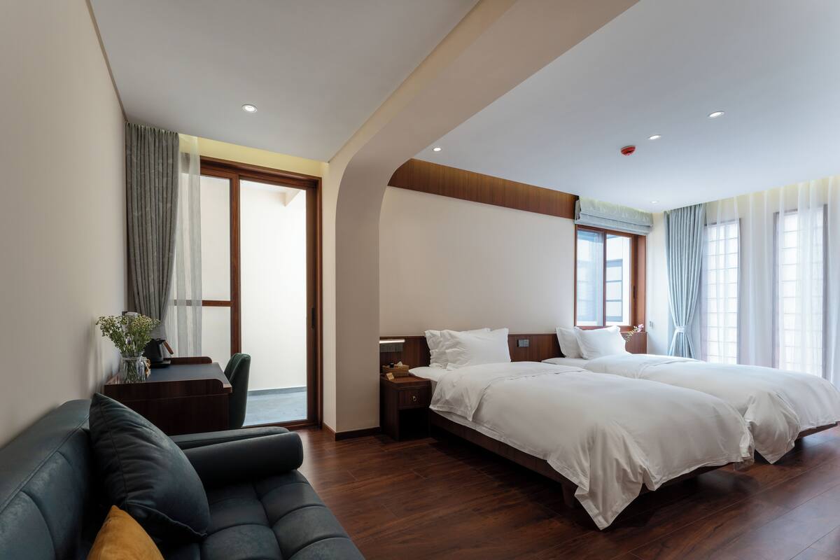 Ein Hotelzimmer mit einem großen Bett, einem Schreibtisch mit Stuhl und Blick ins Freie.