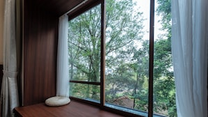 A room with a large window, a wooden bench, and a woven pouf. - Mengxi Bieyuan Forest Resort Hotel (Huangshan)