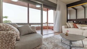 A modern living room with a sofa, a coffee table, and a balcony with a view.