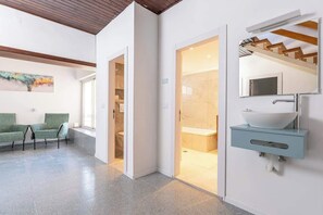 A modern bathroom with a large mirror, a white sink, and a shower area. - Kinneret View  six bedrooms (Tiberias)