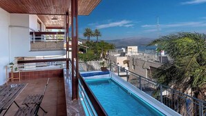 A rooftop pool with a view of palm trees and a distant landscape.