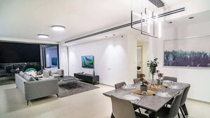 Un soggiorno moderno con zona pranzo, divano, tavolino e televisione.