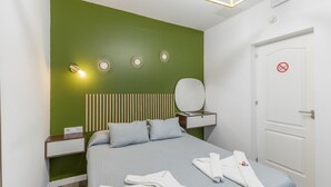 Ett välordnat hotellrum med en säng, sängbord, en spegel och en dörr med en skylt som förbjuder rökning.
