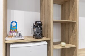 Eine Küchenzeile mit einer Bosch-Kaffeemaschine, einem weißen Kühlschrank und einem Holzregal mit einer Kerze.