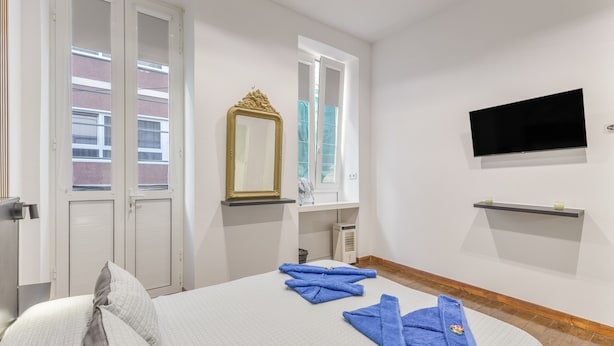 A hotel room with a bed, a TV, a mirror, and a window with a view of buildings. -  'Gran Canaria' with Balcony and Wi-Fi (Las Palmas de Gran Canaria)