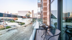 En modern hotellbalkong med ett glasräcke som erbjuder utsikt över stadsbilden och byggarbetsplatsen nedanför.