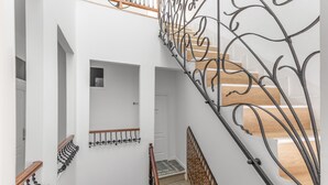 Un escalier avec une rampe en métal, des marches en bois et un mur orné de motifs.