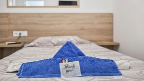 Un lit bien fait, avec une serviette bleue et une carte de remerciement.