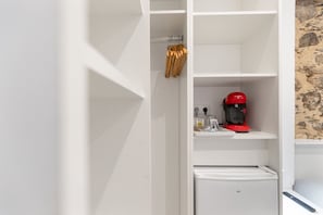 Un meuble de rangement blanc avec des étagères, une machine à café rouge et un petit appareil électroménager.