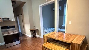 A kitchen with a built-in oven and microwave, a small round table, and a wooden bench.