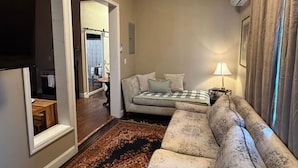 A living room with a sofa, a table, a lamp, and a TV.