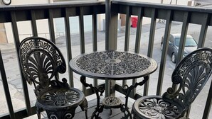 A balcony with ornate metal chairs and a table, featuring intricate designs.