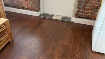 A room with a wooden floor, a door, a brick wall, and a window.