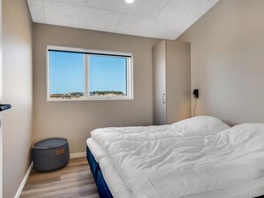 A bedroom with a bed, a window, a wardrobe, and a small ottoman. - "Barthi" - 450m from the sea by Interhome (Harboøre)