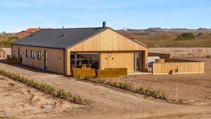 Un edificio moderno de madera con un amplio patio, un garaje y una vista despejada del paisaje circundante.